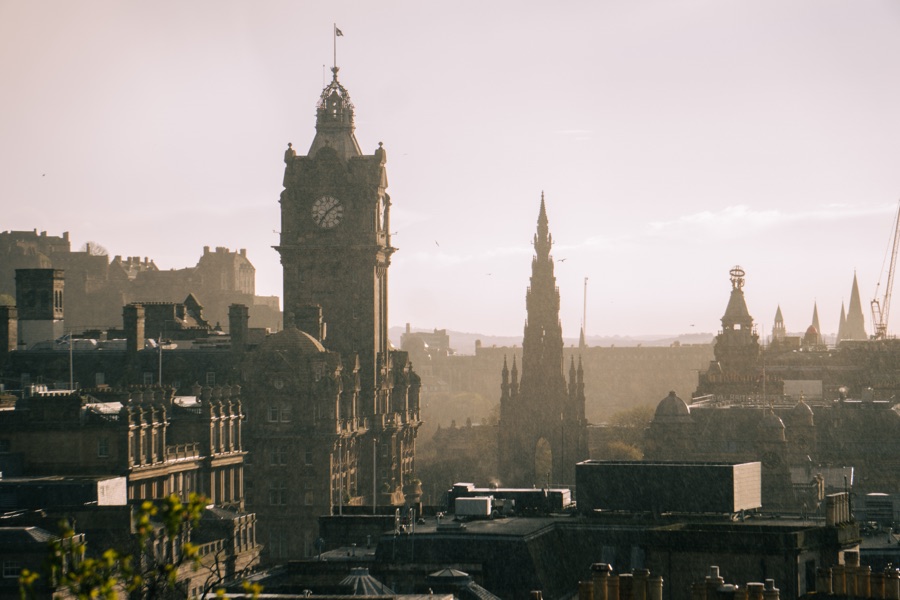 A city skyline with a clock tower and spires in warm afternoon light.
